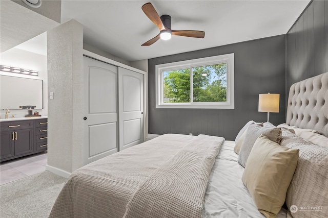 bedroom with ceiling fan, sink, a closet, light carpet, and ensuite bathroom