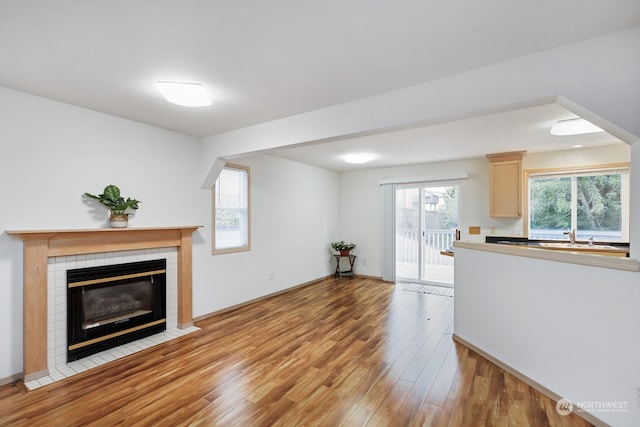 unfurnished living room with a tiled fireplace, light hardwood / wood-style floors, and sink