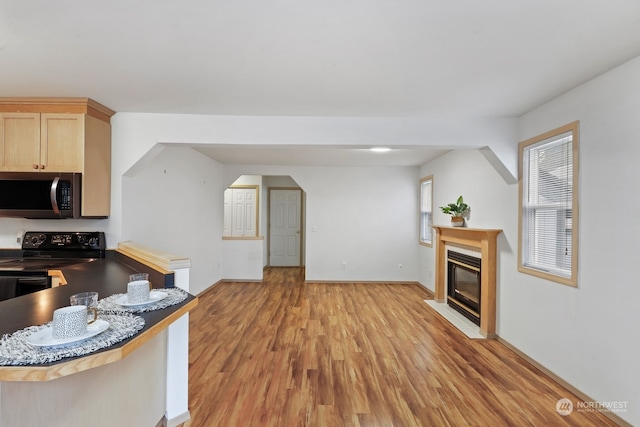 kitchen with light brown cabinets, black electric range, light hardwood / wood-style flooring, and kitchen peninsula