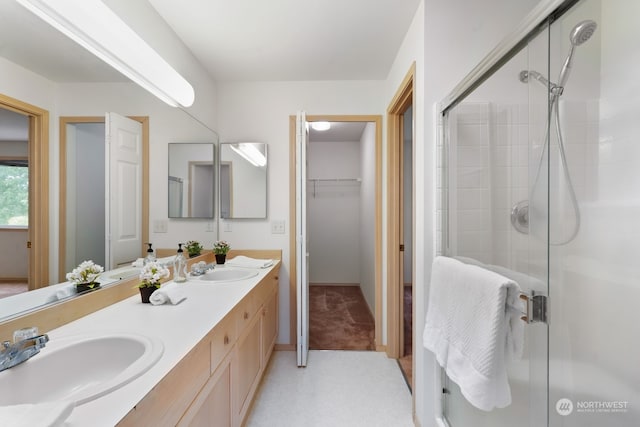 bathroom featuring a shower with door and vanity