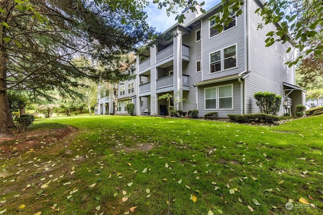 back of property featuring a balcony and a yard