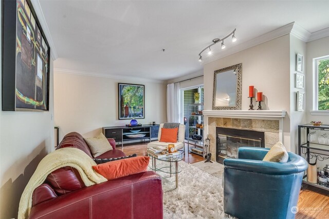 living room with crown molding, a tiled fireplace, and hardwood / wood-style flooring