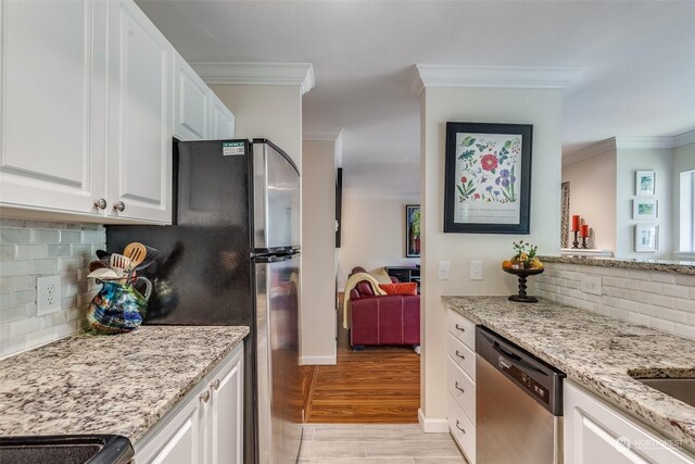 kitchen featuring light hardwood / wood-style flooring, white cabinetry, backsplash, and stainless steel dishwasher