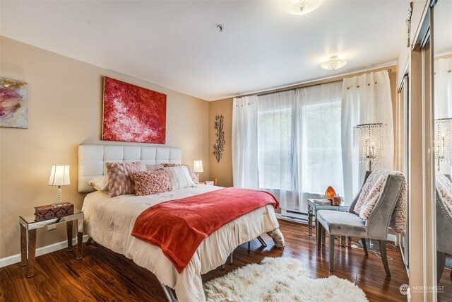 bedroom with a baseboard heating unit and dark hardwood / wood-style flooring