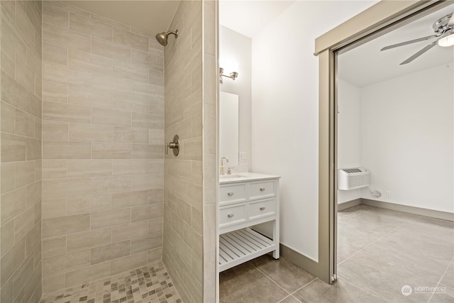 bathroom featuring ceiling fan, vanity, a tile shower, tile patterned floors, and an AC wall unit