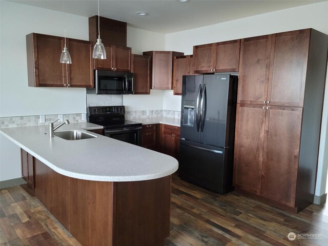 kitchen with dark wood-type flooring, kitchen peninsula, black appliances, decorative light fixtures, and sink