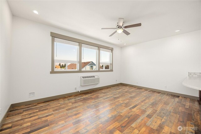 spare room featuring ceiling fan, dark hardwood / wood-style floors, and a wall mounted air conditioner