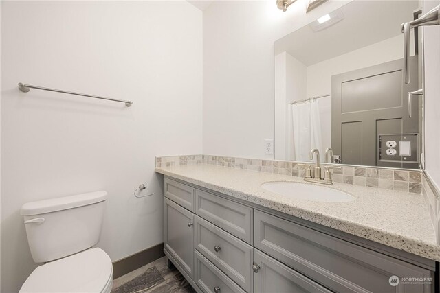 bathroom with wood-type flooring, vanity, and toilet