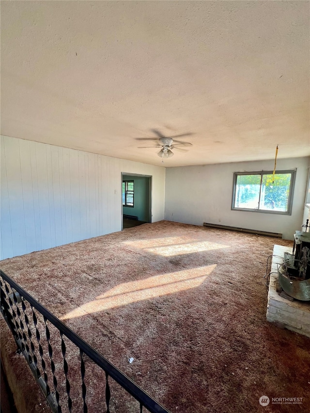 interior space featuring carpet floors, a textured ceiling, a wood stove, and ceiling fan