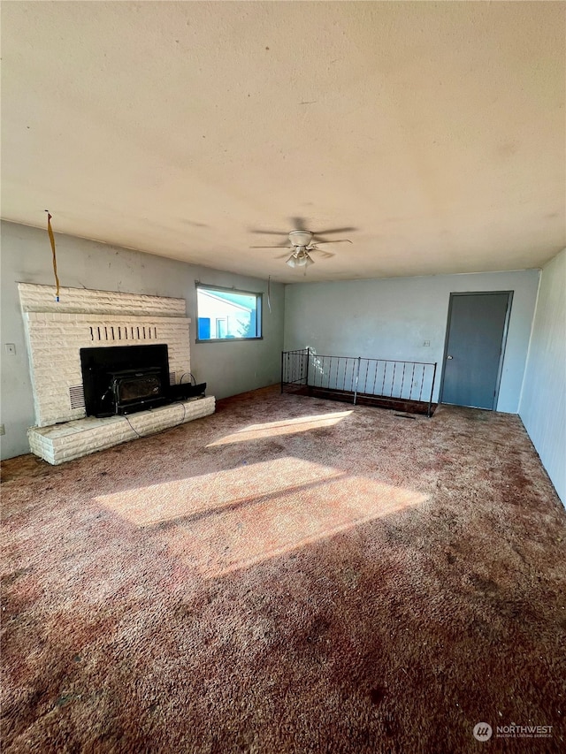 unfurnished living room featuring ceiling fan, carpet floors, a fireplace, and a textured ceiling