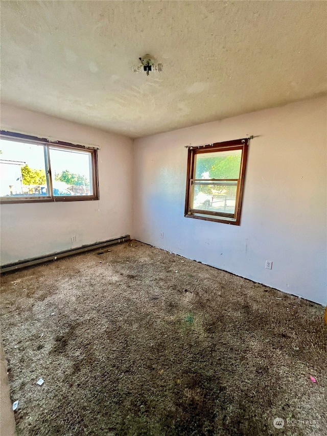 carpeted spare room featuring a textured ceiling and a healthy amount of sunlight