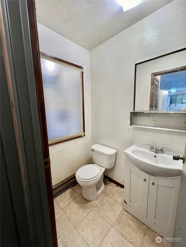 bathroom with tile patterned flooring, a textured ceiling, vanity, and toilet