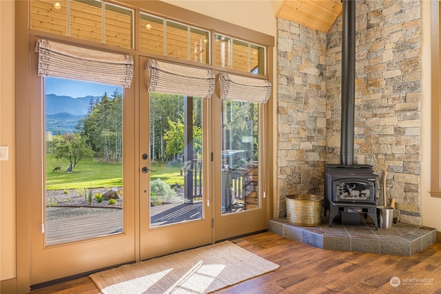 doorway to outside featuring a wood stove, vaulted ceiling, hardwood / wood-style floors, and a mountain view