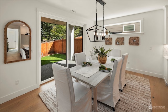 dining room with light hardwood / wood-style floors and an inviting chandelier