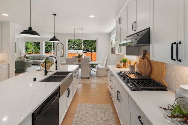 kitchen with white cabinets, light hardwood / wood-style floors, appliances with stainless steel finishes, and tasteful backsplash