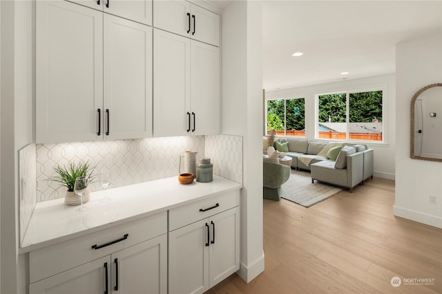 kitchen with white cabinets, light hardwood / wood-style flooring, and tasteful backsplash