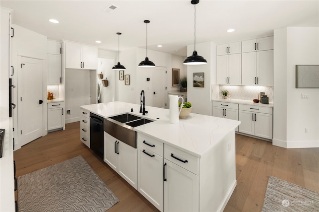 kitchen with light hardwood / wood-style floors, an island with sink, white cabinets, black dishwasher, and decorative light fixtures