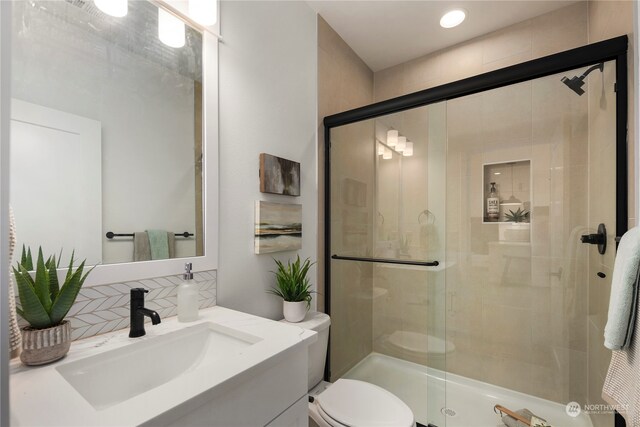 bathroom featuring walk in shower, vanity, toilet, and tasteful backsplash