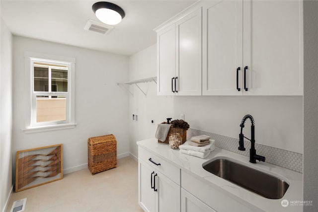 kitchen with light stone countertops, white cabinetry, and sink