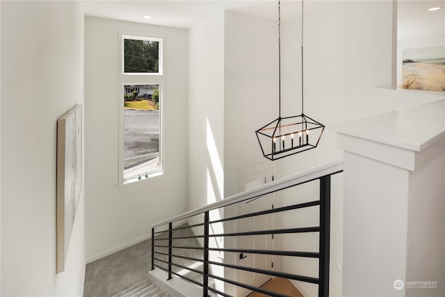 staircase featuring plenty of natural light, a chandelier, and carpet