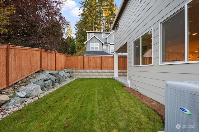 view of yard with a fenced backyard and central AC unit