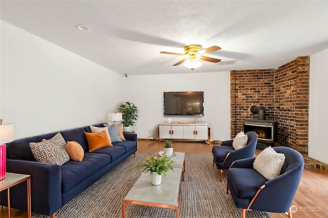 living room featuring a wood stove, ceiling fan, and hardwood / wood-style flooring