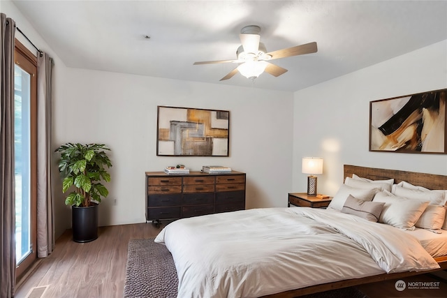 bedroom with multiple windows, ceiling fan, and hardwood / wood-style flooring