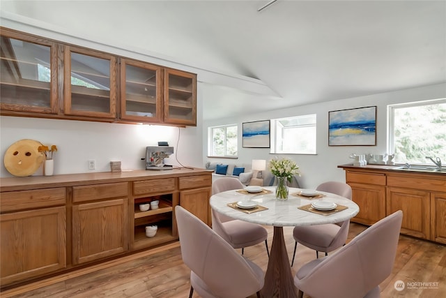 dining space with vaulted ceiling, light hardwood / wood-style flooring, and sink