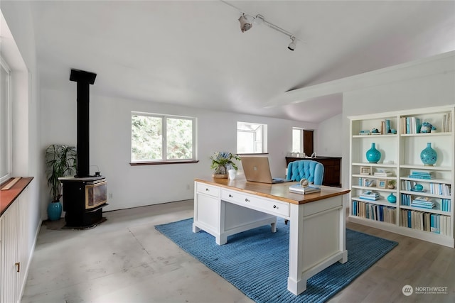 office space with lofted ceiling, track lighting, a wood stove, and light hardwood / wood-style flooring