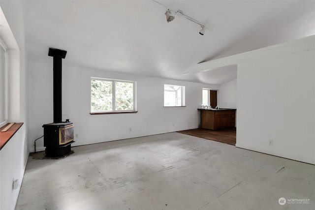 interior space featuring a wood stove, lofted ceiling, sink, and rail lighting