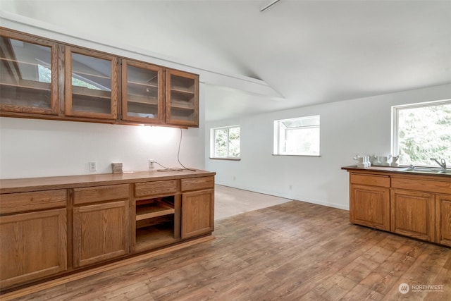 kitchen with vaulted ceiling, light hardwood / wood-style flooring, and sink