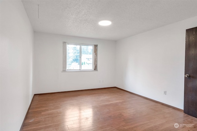 empty room featuring light hardwood / wood-style floors and a textured ceiling