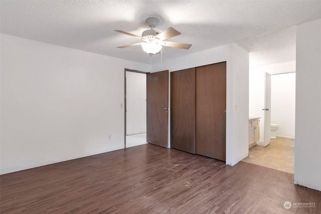 unfurnished bedroom with ceiling fan, hardwood / wood-style flooring, a closet, and a textured ceiling