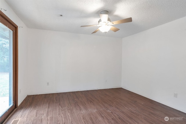 empty room with a healthy amount of sunlight, ceiling fan, and dark wood-type flooring