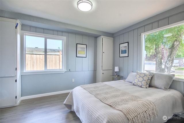 bedroom with wood finished floors, baseboards, and multiple windows