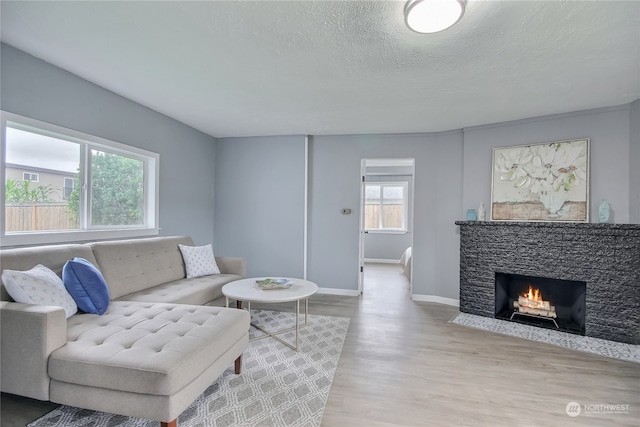 living room with light hardwood / wood-style floors, a fireplace, and a textured ceiling