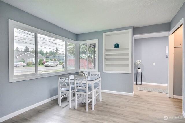 dining space featuring a textured ceiling, light hardwood / wood-style flooring, and built in features