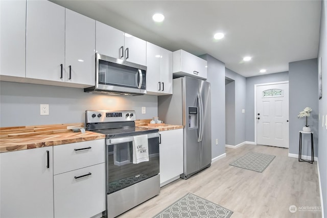 kitchen with white cabinets, baseboards, appliances with stainless steel finishes, and light wood finished floors