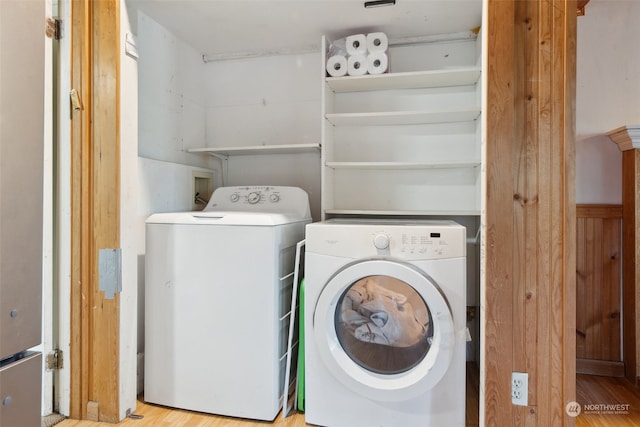 laundry room with washing machine and clothes dryer and light hardwood / wood-style floors