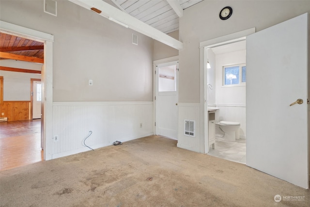 unfurnished bedroom with connected bathroom, wood walls, heating unit, carpet, and wooden ceiling