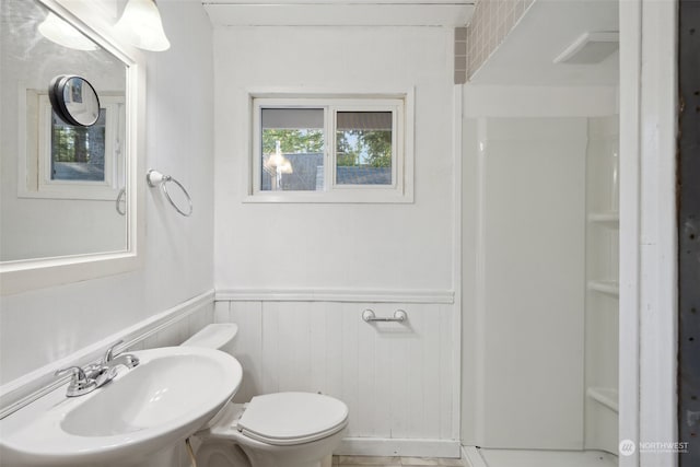 bathroom featuring wood walls, sink, and toilet