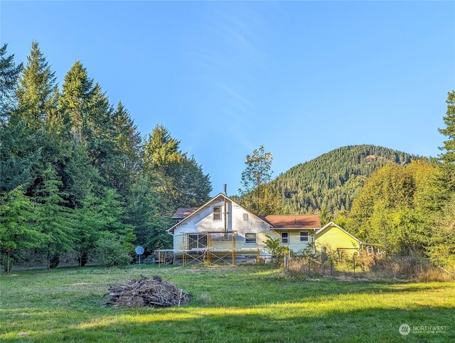 back of property with a mountain view and a yard