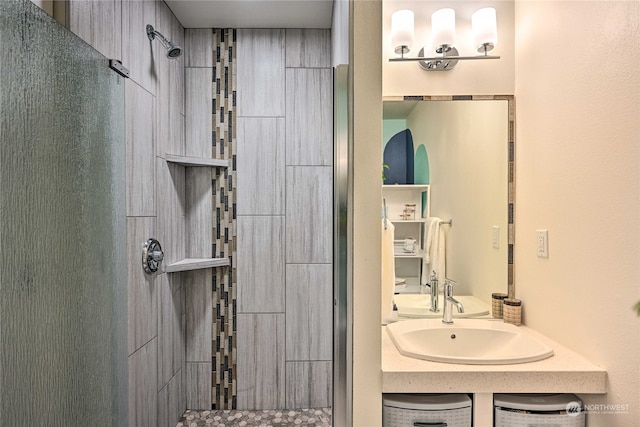 bathroom featuring a shower with shower door and sink