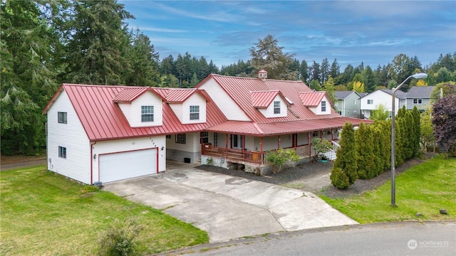 view of front of home featuring a standing seam roof, a porch, metal roof, a front lawn, and driveway