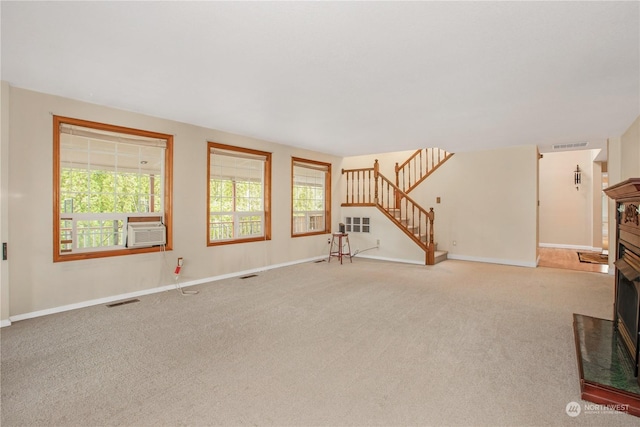 unfurnished living room with a fireplace, carpet, visible vents, and stairs