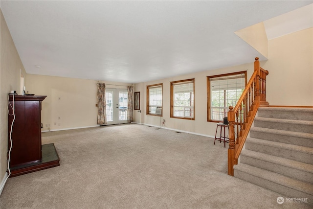 unfurnished living room with baseboards, carpet, and stairs