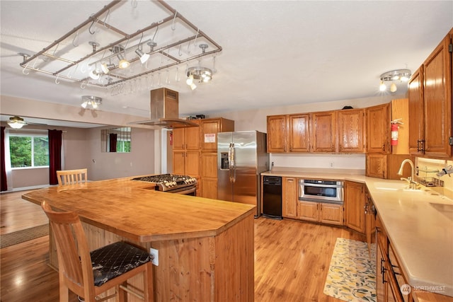 kitchen featuring light wood-style floors, brown cabinetry, light countertops, stainless steel appliances, and island range hood
