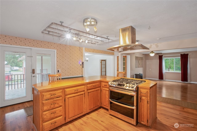 kitchen featuring light hardwood / wood-style flooring, island range hood, wooden counters, and double oven range