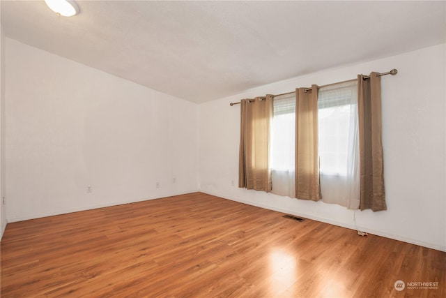 unfurnished room featuring visible vents and wood finished floors