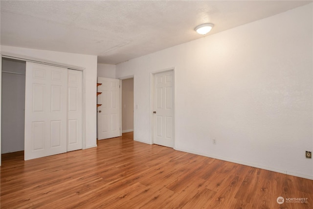 unfurnished bedroom with wood finished floors, a closet, and baseboards